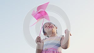 Happiness little girl smiling in wheat field holding small wind wheel or windmill toy on hand