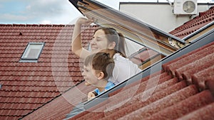 Happiness of a mother and her son as they open attic windows and peer outdoors, symbolizing the essence of family joy