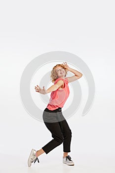 Excited beautiful young redheaded woman dancing isolated on white studio background. Human emotions, facial expression