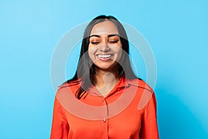 Happy young Indian woman closing her eyes and smiling, studio