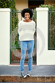 Happiness is right on your doorstep. Portrait of a happy young woman standing on the sidewalk outside of her home.