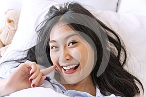 Happiness smiling woman using smartphone for selfie on the bed for social media. Cheerful girl lying on white bed taking