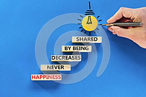 Happiness symbol. Concept words Happiness never decreases by being shared on wooden block. Businessman hand. Beautiful blue table