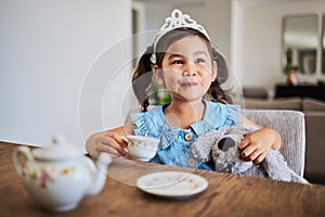 Happiness, tea party and child in her home, playing, having fun with tea set and wearing a crown. Creativity