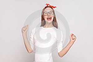 happiness and victory portrait of beautiful emotional young woman in white t-shirt with freckles, black glasses, red lips and