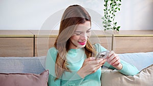 Happiness young asian woman smile sitting on sofa using smart phone with cozy in living room at home.