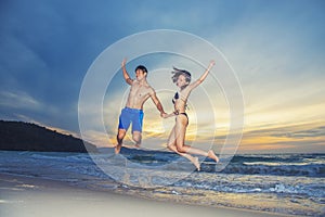 Happiness young couple jumping with happy on the beach at sunset. Vacation and freedom travel. Love, wedding and valentine concept