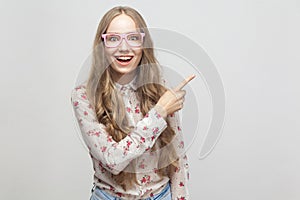 Happiness young girl, showing finger at copy space and looking a