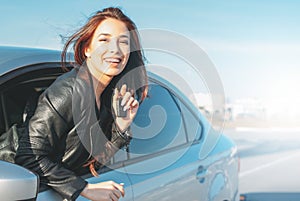 Happpy beautiful charming brunette long hair young asian woman in black leather jacket with key in car window