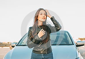 Happpy beautiful charming brunette long hair young asian woman in black leather jacket near her car