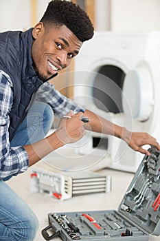 Happpy plumber with toolbox near washing machine