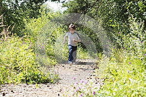 happy 10 year old boy runs along the forest road.