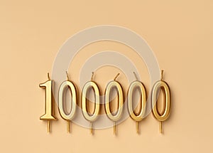 Happy 100000 celebration festive background made with golden candles in the form of number hundred thousand lying on sparkles