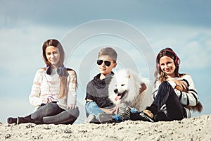 Happy 11 year old boy hugging his dog breed Samoyed at the seashore against a blue sky close up. Best friends rest and