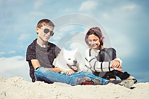Happy 11 year old boy hugging his dog breed Samoyed at the seashore against a blue sky close up. Best friends rest and