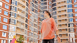 A happy 16-year-old girl enjoys freedom with her arms outstretched against the background of high-rise buildings.