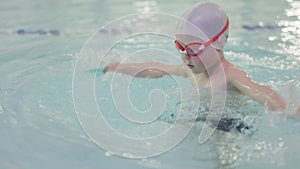 happy 3-4 year child kid boy training in swimming pool wearing goggles, cap