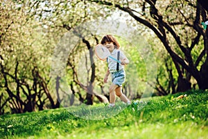 Happy 3 years old child boy catching butterflies with net on the walk in sunny garden or park. Spring and summer outdoor activitie