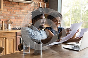 Happy 30s african ethnicity biracial family couple involved in paperwork.