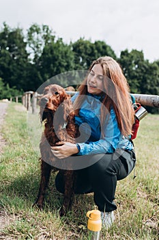 Happy 30s Girl loving and hugging tightly her dog. Travel and hiking with pet. Redhead Woman in active trekking clothes