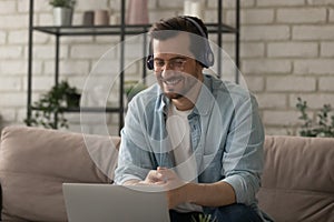 Happy 30s man in glasses and headphones holding online video call.