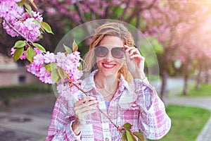 Happy 30s woman adjusting sunglasses in park