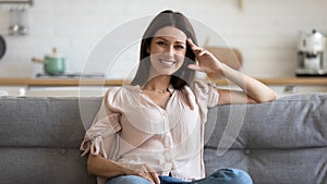 Happy 30s woman sitting on cozy sofa in living room.