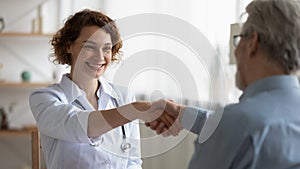 Happy 35s young female physician shaking hands with patient.