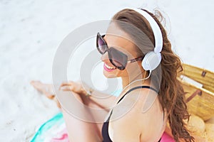 Happy 40 year old woman on white beach listening to music