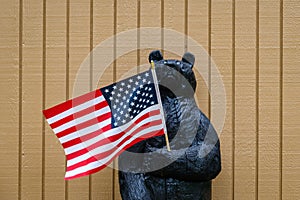 Happy 4th of July, wooden bear holding a US Flag, patriotic background