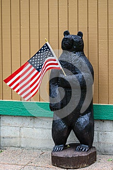 Happy 4th of July, wooden bear holding a US Flag, patriotic background