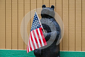 Happy 4th of July, wooden bear holding a US Flag, patriotic background