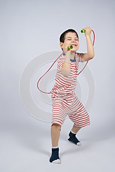 Happy 5 year old boy jumping rope on a white background, a place for text
