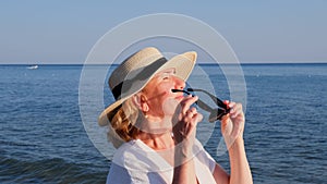 happy 50 year old woman in straw hat and sunglasses enjoying the sun against the blue sea background. Summer, vacation