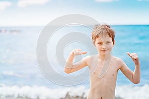 Happy 7 years boy in victory success gesture on the beach.