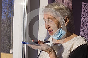 Happy 70s grandmother hold smartphone record audio message talking on gadget at home