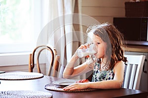 happy 8 years old child girl having breakfast in country kitchen