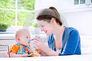 Happy aby boy eating his first solid food witn his mother