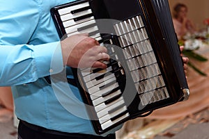 Happy accordion musician playing at wedding reception, hand on h
