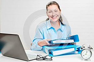 Happy accountant with folders at the table on a bricky white wall background