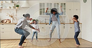 Happy active african american family dancing in kitchen.