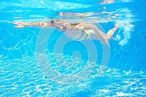 Happy active child swims freestyle in pool, underwater view