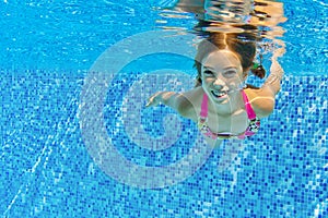 Happy active child swims underwater in pool