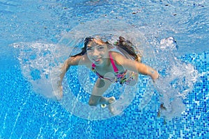 Happy active child swims underwater in pool