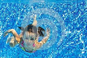 Happy active child swims underwater in pool