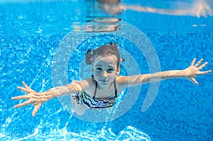 Happy active child swims underwater in pool