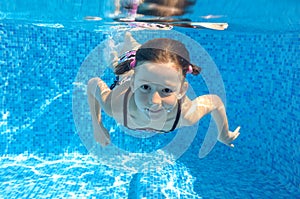 Happy active child swims underwater in pool