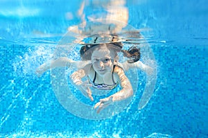 Happy active child swims underwater in pool