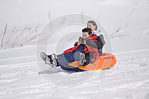 Happy active delightful little sport boy and girl riding on tubing on white snow alpine ski slope during winter vacation