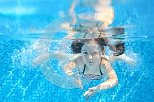 Happy active girl swims underwater in pool